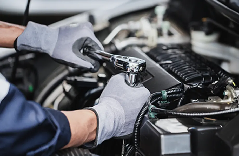 整備士がエンジンルーム内でラチェットレンチを使って整備作業を行っている場面