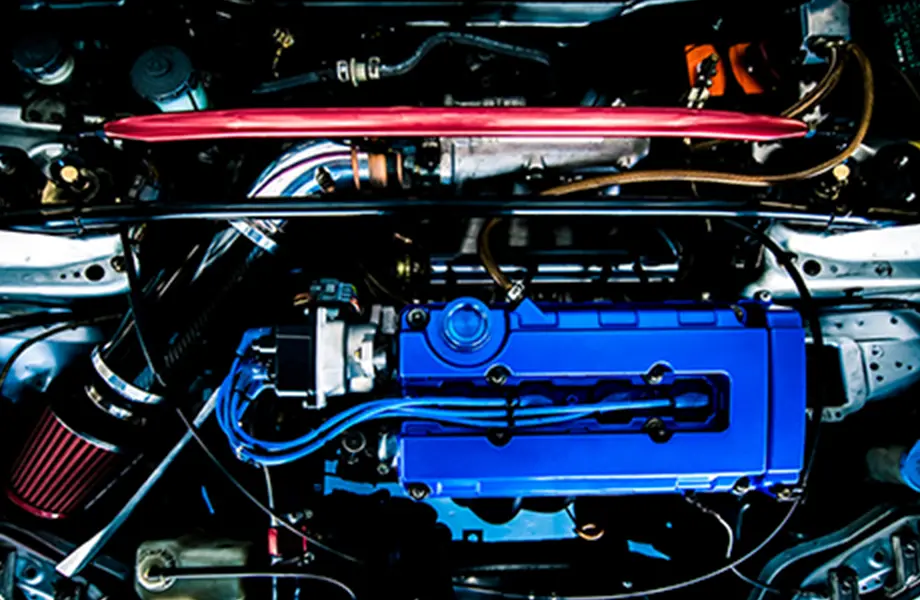 青いエンジンカバーと赤い補強バーが目立つ、カスタムチューンされた車のエンジンルームの様子