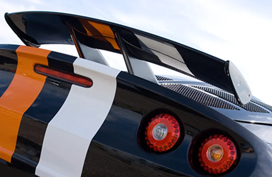車のリアウイングが特徴的なスポーツカー、オレンジと白のストライプが施されている
