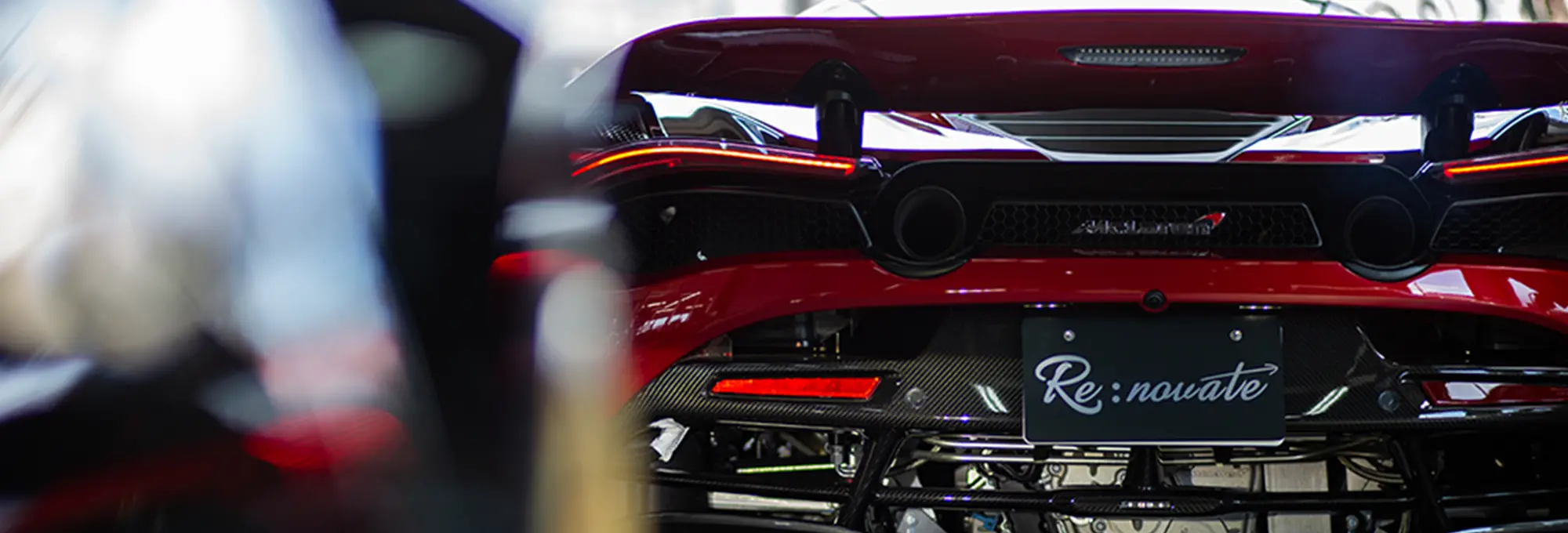 赤いスポーツカーのリア部分、カーボンファイバーのディテールと独特のテールランプが見える