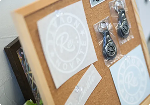 コルクボードにRe:novateロゴのステッカーやキーホルダーがディスプレイされている様子