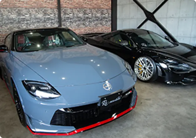 グレーと黒のスポーツカーが室内展示され、Re:novateナンバープレートが付けられている様子