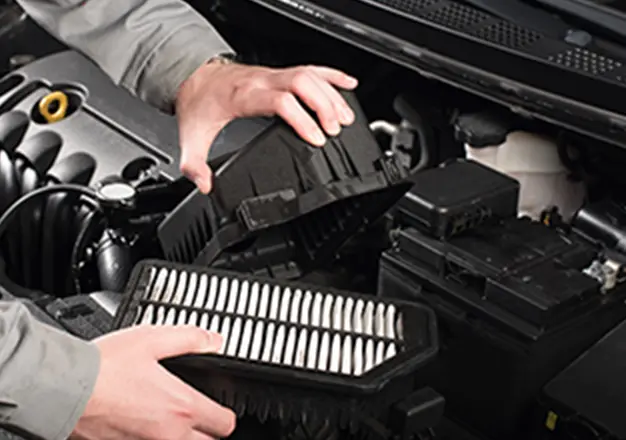 自動車のエンジンルーム内でエアフィルターを交換している整備作業の様子