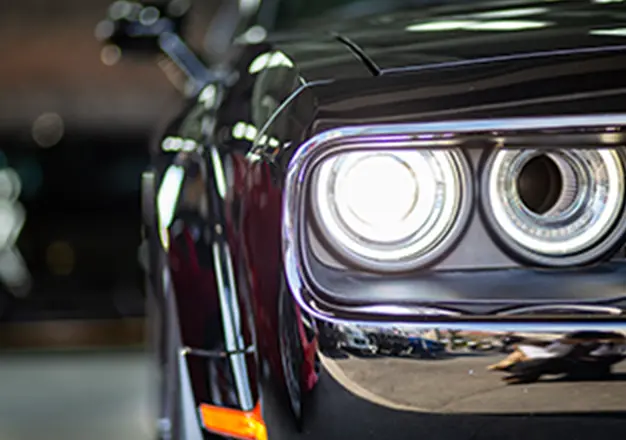 ヘッドライトが点灯した黒い車のフロント部分、迫力あるデザインが目立つ