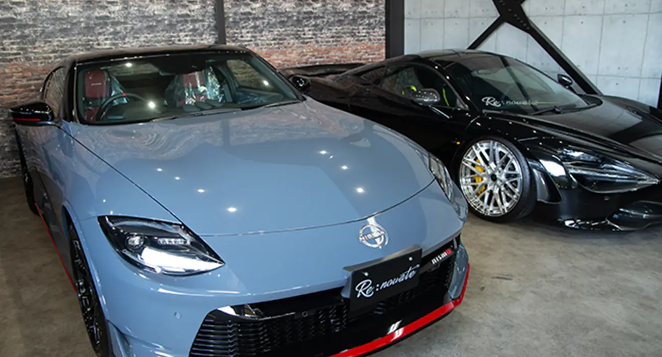 室内に展示されたスポーツカー2台、手前はブルーの車、奥は黒の高級車が並ぶショールーム