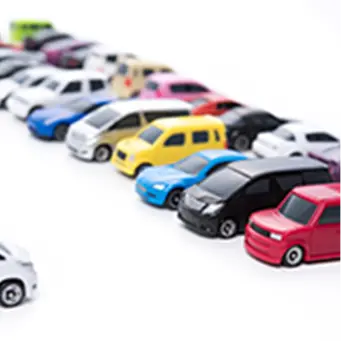 色とりどりのミニカーが一直線に並べられた、白背景のイメージ