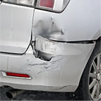 バンパー部分に大きなへこみと傷があるシルバーの車の後部