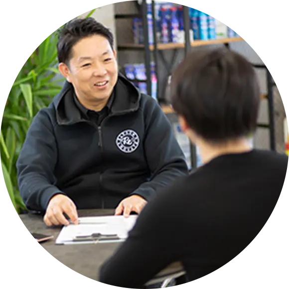 デスクで顧客と向かい合い、書類をもとに説明をする男性スタッフ