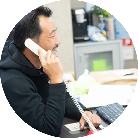 電話対応中の男性スタッフが笑顔で受話器を持ち応対している