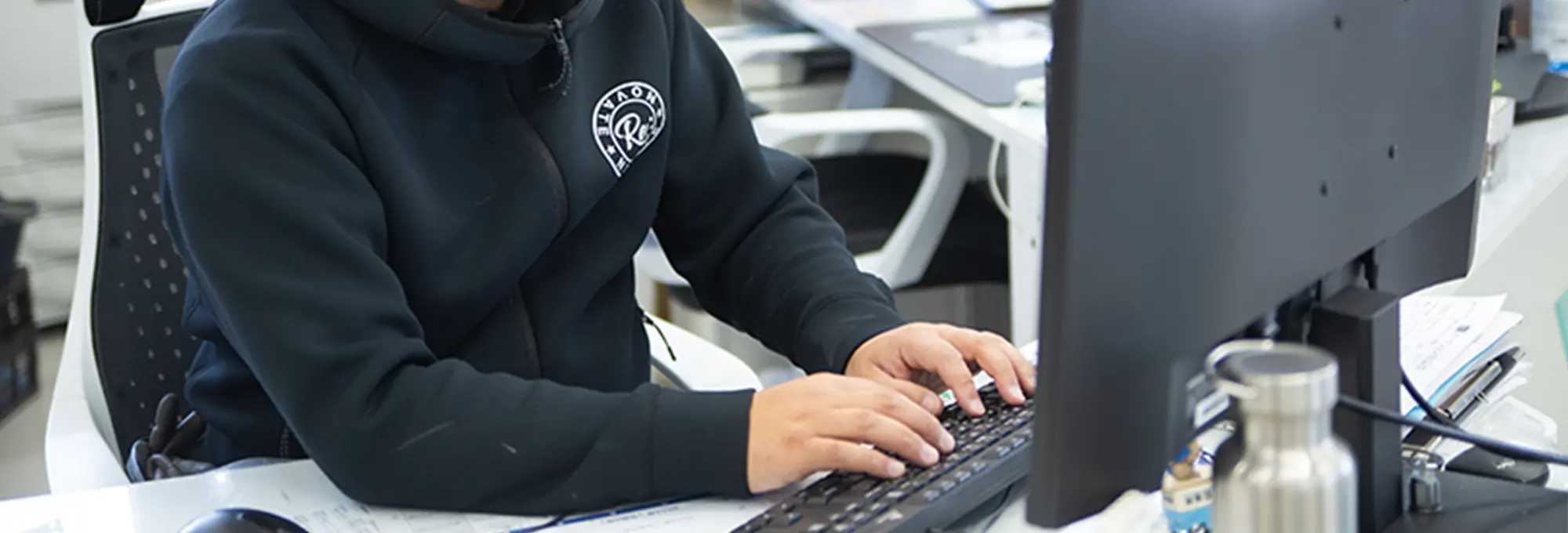 オフィスでパソコン作業をするスタッフの手元とモニター