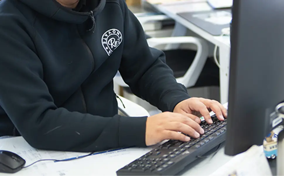 オフィスでパソコン作業をするスタッフの手元とモニター