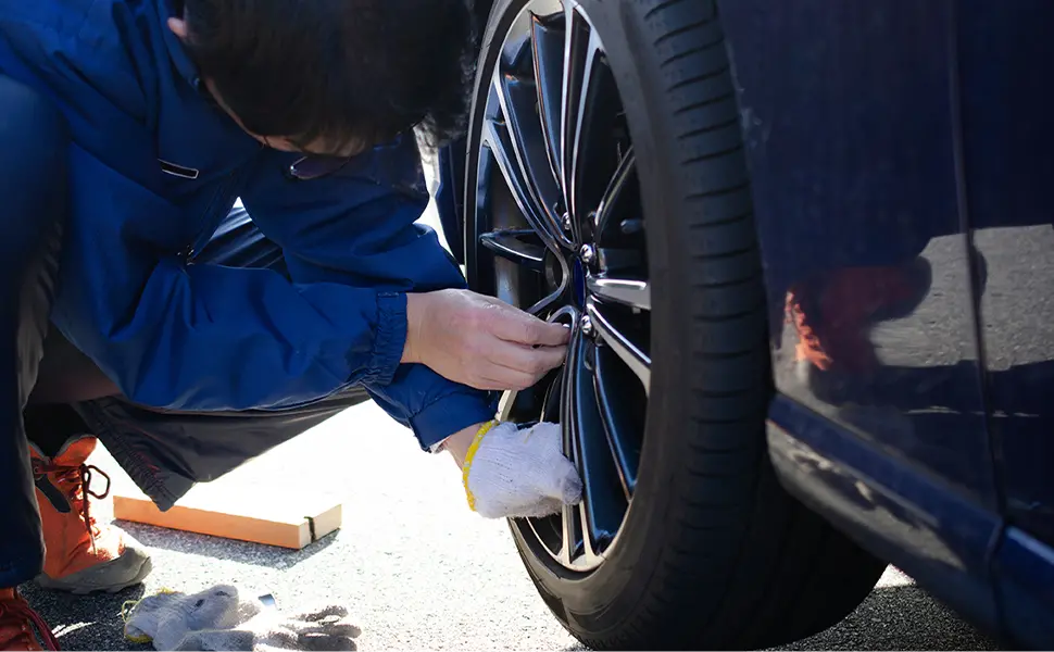 青色のスポーツカーのホイールの作業する男性