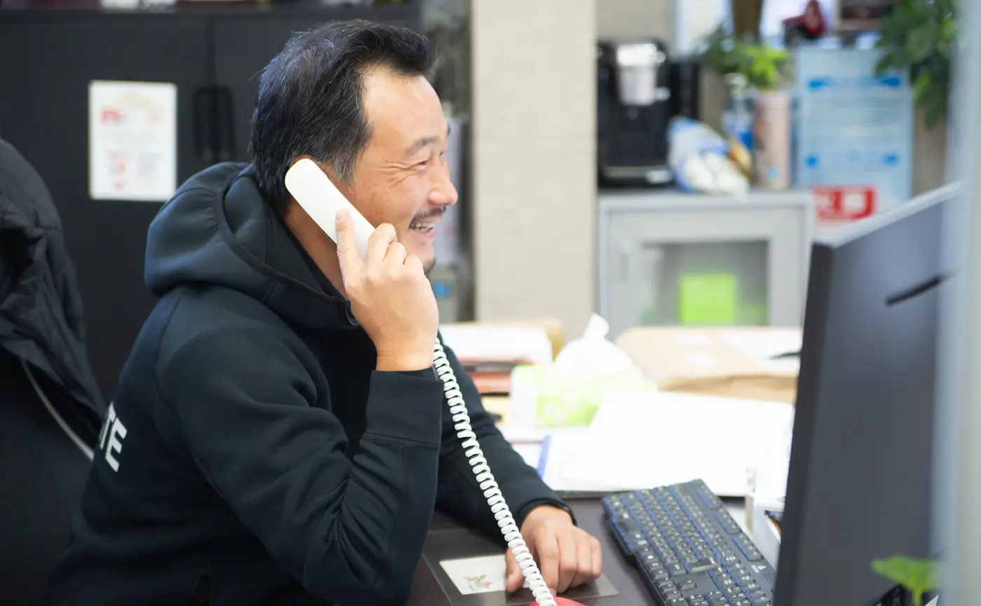 事務所で電話をしている笑顔の男性